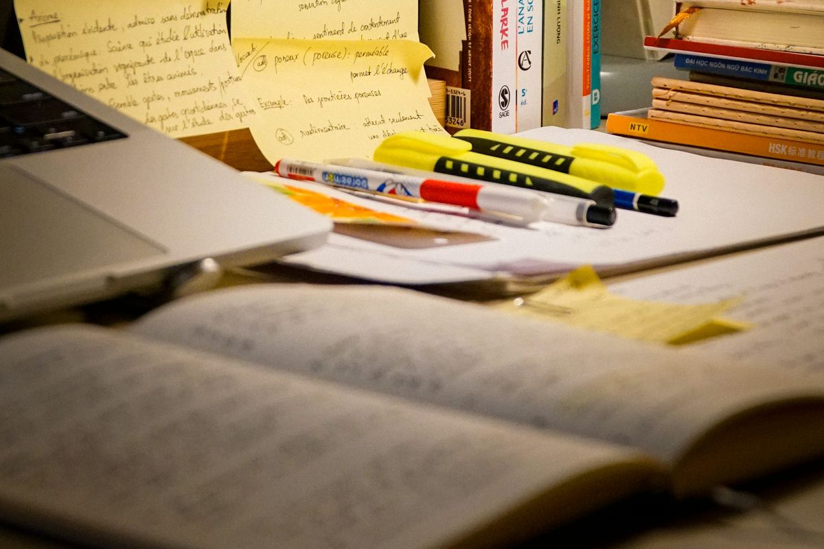 A cozy study desk with an open notebook, highlighters, and sticky notes covered in handwritten vocabulary